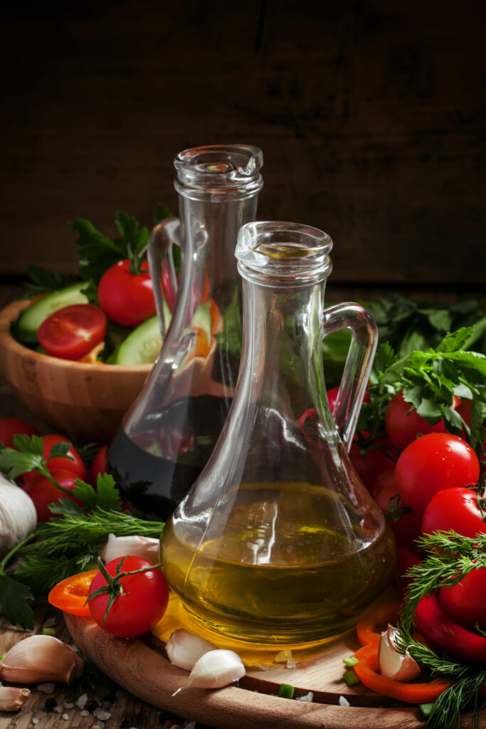 fresh olive oil in glass carafe with tomatoes, peppers, cucumber