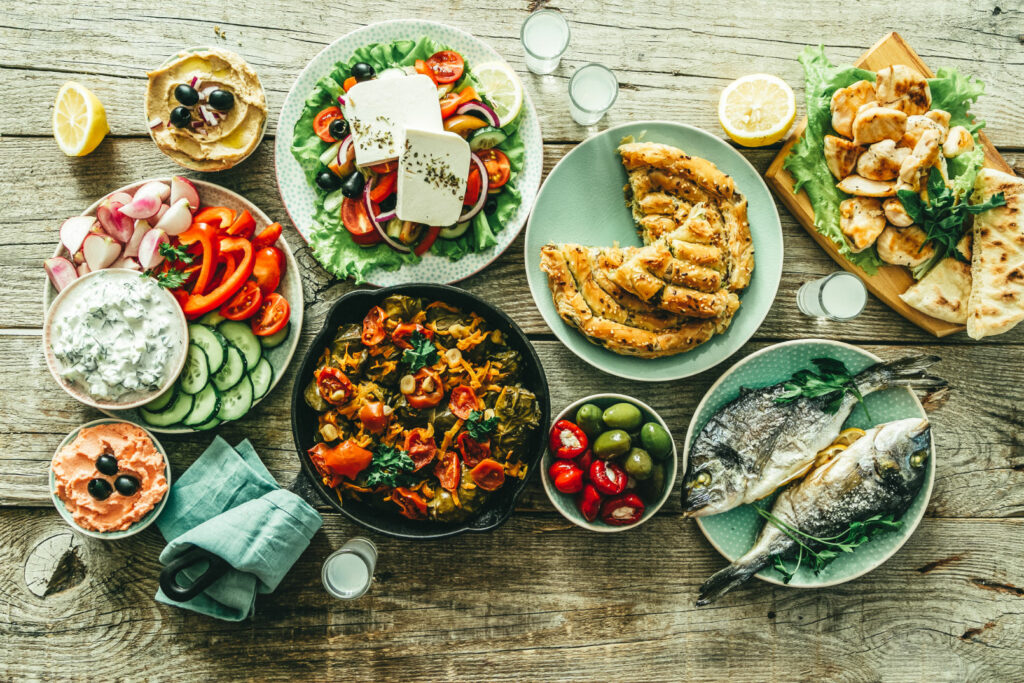 selection of traditional greek food salad, meze, pie, fish, tzatziki, dolma on wood background